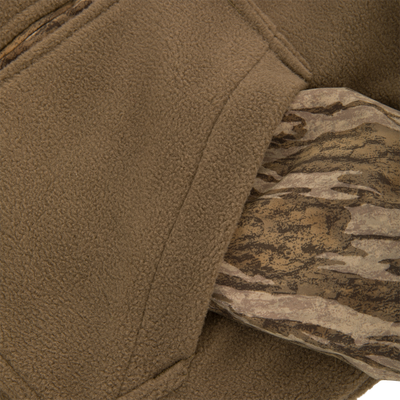 Close-up of the MST Youth Eqwader Full Zip Jacket's textured tan fleece and woodland camouflage fabric, highlighting its innovative dual-zone, moisture-wicking design for optimal comfort in varying conditions.