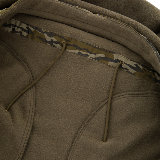 BFCM - MST Camo Eqwader 1/4 Zip Jacket close-up shows textured fleece, camo-patterned hood binding, and drawcords, emphasizing Drake's innovative, breathable waterfowl gear.