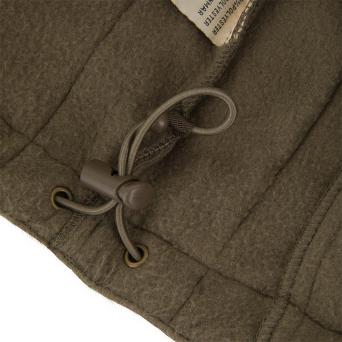 Close-up of BFCM - MST Camo Eqwader 1/4 Zip Jacket's hem, showcasing draw-cord with toggle and part of care label, highlighting Drake Waterfowl's advanced design.