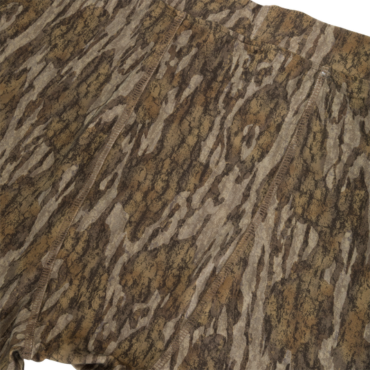 Close-up of Drake Base Layer Bottoms featuring moisture-wicking fabric in a brown and tan tree bark camouflage pattern with visible seams.