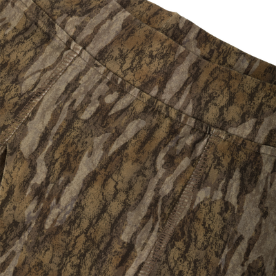 Close-up of Drake Base Layer Bottoms featuring a brown and grey bark-inspired camouflage pattern with visible stitched seams at the waistband and crotch.