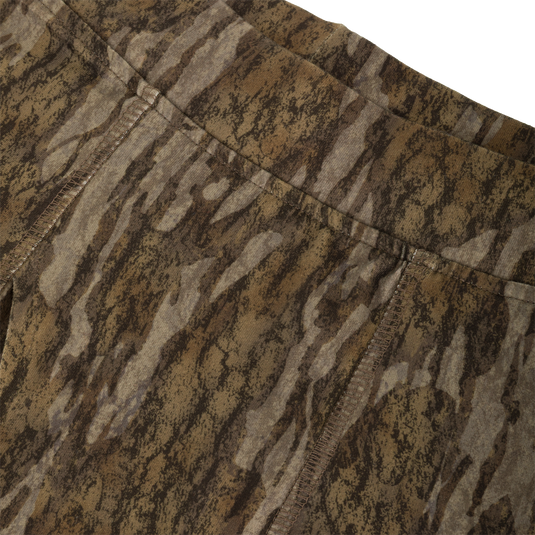Close-up of Drake Base Layer Bottoms featuring a brown and grey bark-inspired camouflage pattern with visible stitched seams at the waistband and crotch.