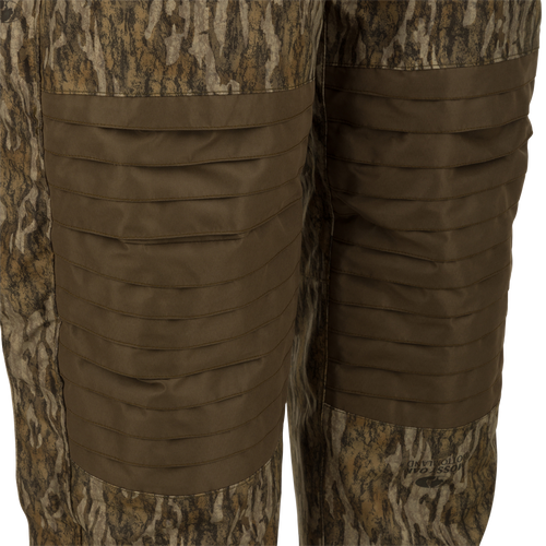 LST Guardian Elite Bibs provide ultimate full-body cover-up for hunters in frigid weather. Waterproof, windproof, and breathable, with reinforced knees and seat. Features include Magnattach™ chest pocket, call separator, handwarmer pockets, and side leg zippers for easy on/off. Stay warm and protected with Drake Waterfowl's high-quality hunting gear. (120 characters)