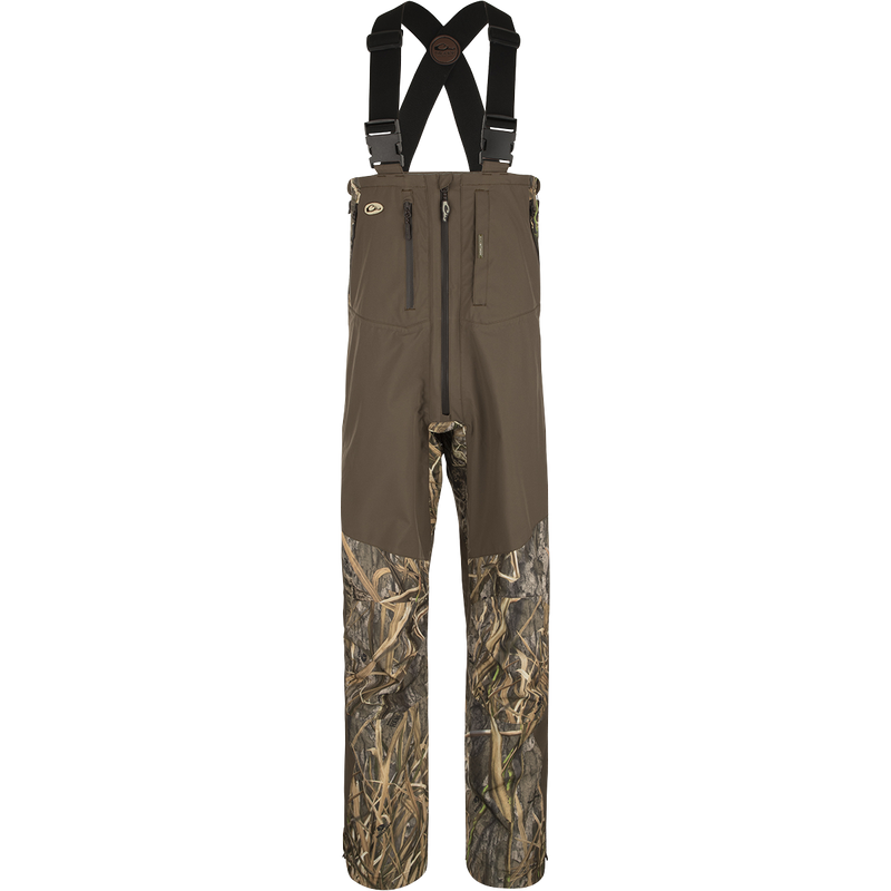 A close-up of the EST Guardian Elite Pro Ultralight 3-Layer Bibs, featuring a brown and black pants with straps, camouflage shorts, and a black strap with a brown logo.