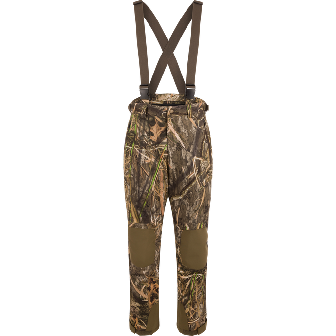 MST Waist-High Insulated Bibs with camouflage pattern, suspenders, and multiple zippered pockets for secure storage; designed for hunting with waterproof, insulated material.