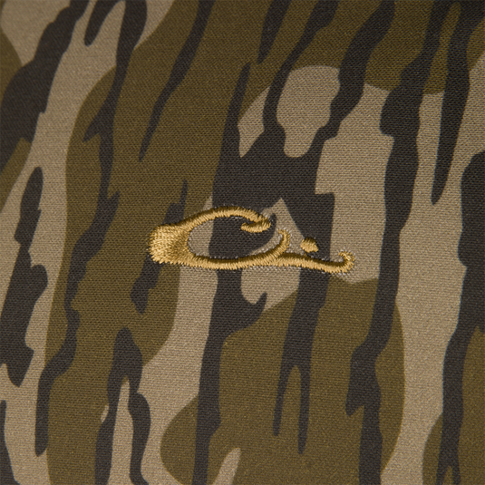 Close-up of the brown and green camouflage fabric of a Waterfowl LST Insulated Waxed Cotton Jacket, featuring an embroidered gold duck head logo in the center.