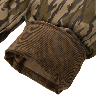 Close-up of a brown ribbed cuff on the sleeve of a camouflage-patterned LST Insulated Waxed Cotton Jacket.