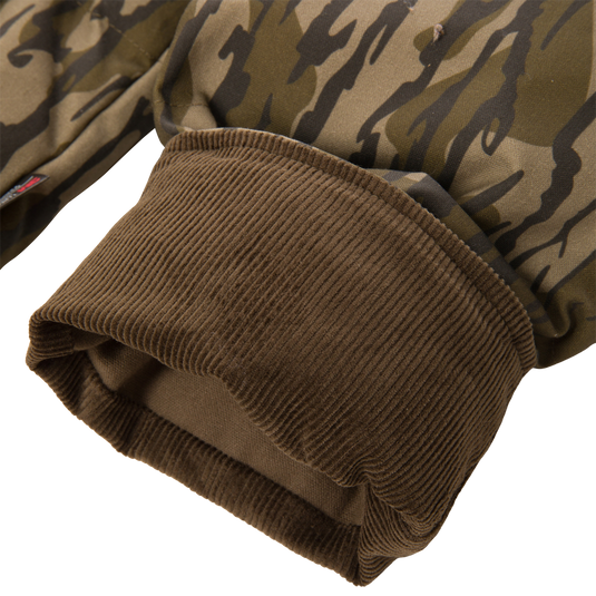 Close-up of a brown ribbed cuff on the sleeve of a camouflage-patterned LST Insulated Waxed Cotton Jacket.