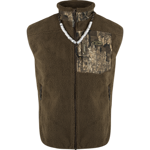 A brown vest with a silver necklace, made of 100% polyester deep pile sherpa fleece. Windproof membrane for protection. Magnattach™ chest pockets and zippered lower pockets. MST Sherpa Fleece Hybrid Liner Vest.