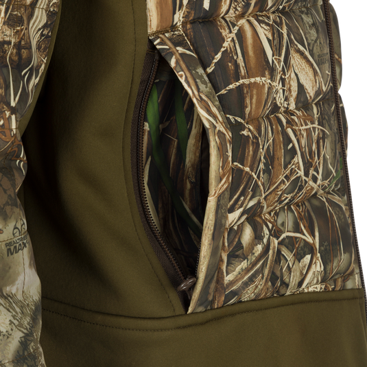 A close-up of a khaki jacket with a zipper and fabric details. The LST Double Down Endurance Hybrid Liner - Realtree by Drake Waterfowl.