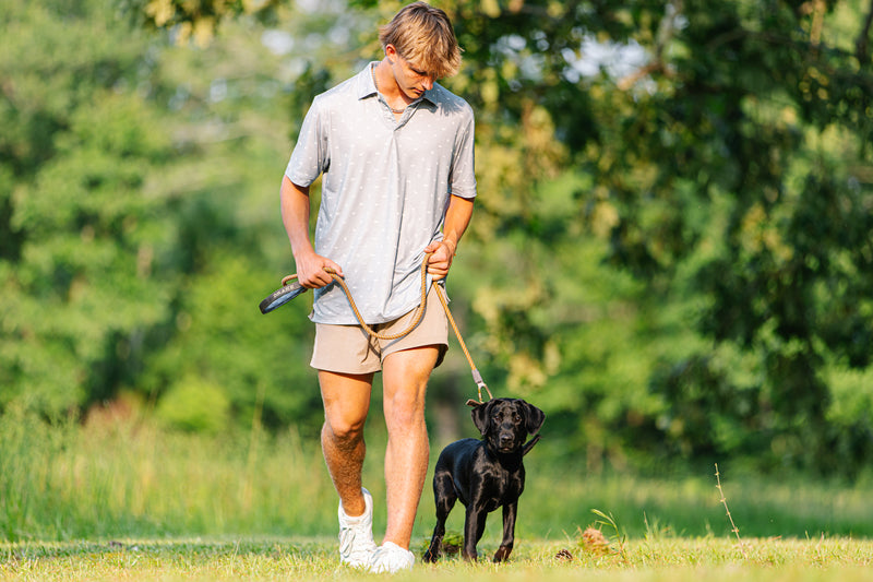 Young man walks a black Labrador puppy with the Team Gun Dog Rope Leash, showcasing its durable, reflective design and padded handle for comfort.