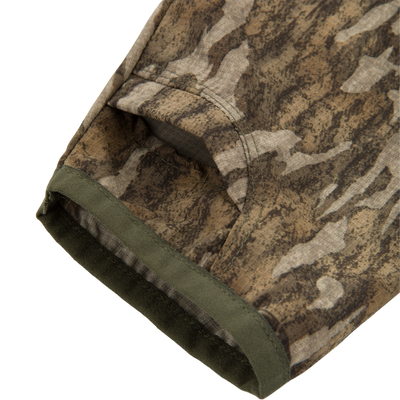 Close-up of the RTL - Half Zip Pullover with Spider Web Technology, highlighting the camo-patterned fabric, stitched seam, and ergonomic thumbhole for enhanced turkey hunting performance.