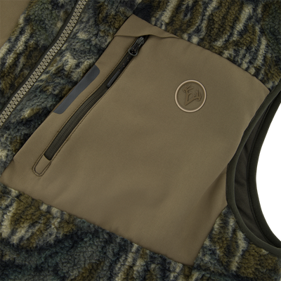 Close-up of Non-Typical Statix Sherpa Fleece Insulated Vest showcasing camo-style sherpa fleece, tan soft-shell panel with zippered pocket, and antler logo badge.