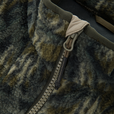 Non-Typical Statix Sherpa Fleece Insulated Vest close-up, showcasing its fuzzy fabric, olive zipper with corded pull, and NON-TYPICAL branding on the zipper.