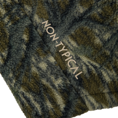 Close-up of the Non-Typical Statix Sherpa Fleece Insulated Vest, showcasing its fuzzy, camouflage-patterned fabric with NON-TYPICAL lettering, ideal for versatile hunting.