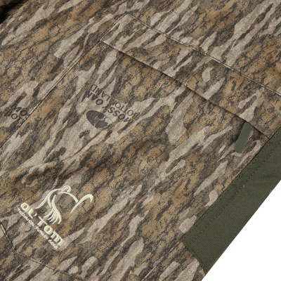 Close-up of a camouflage jacket pocket featuring the Turkey Pant with Spider Web Technology, highlighting its stretch fabric and reinforced, water-resistant design for hunting.