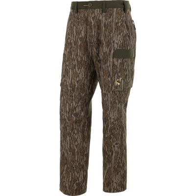 Ol' Tom Tech Stretch Turkey Pants with Mossy Oak Bottomland camo, featuring zippered pockets, flap cargo pocket, embroidered deer logo, and articulated knees for mobility in turkey hunting.