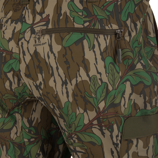 Ol' Tom Tech Stretch Turkey Pants featuring a close-up of camouflage fabric with zipper details, highlighting the hidden stretch waistband and large cargo pockets for hunting functionality.