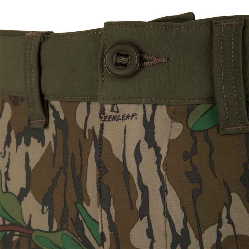 Close-up of Ol' Tom Tech Stretch Turkey Pants, highlighting camouflage pattern, button detail, and breathable mesh pockets for hunting flexibility.