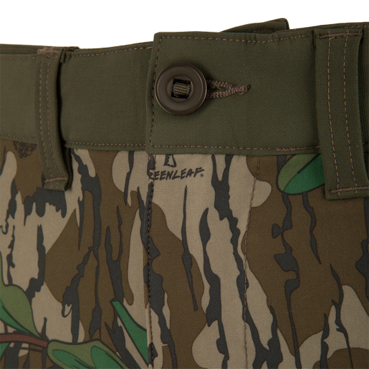 Close-up of Ol' Tom Tech Stretch Turkey Pants, highlighting camouflage pattern, button detail, and breathable mesh pockets for hunting flexibility.