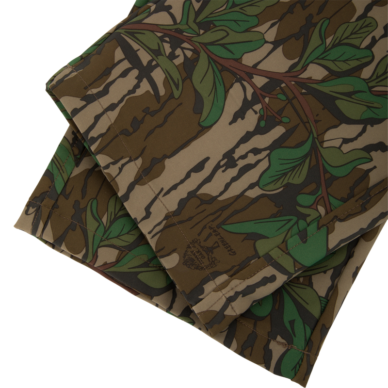 Ol' Tom Tech Stretch Turkey Pants with camouflage pattern, showcasing folded fabric designed for flexibility and comfort, featuring cargo pockets and breathable mesh areas.