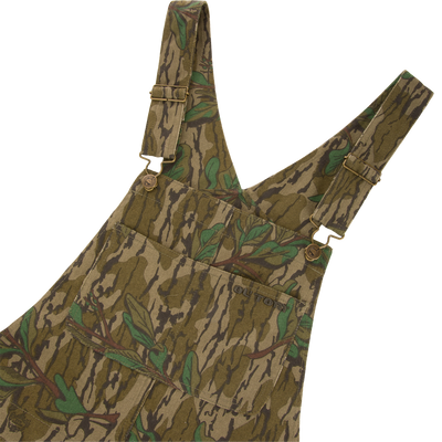 Throwback 80 Field Bib featuring camouflage design, metal button details, triple needle stitching, and reinforced knees, ideal for durable use in demanding hunting environments.