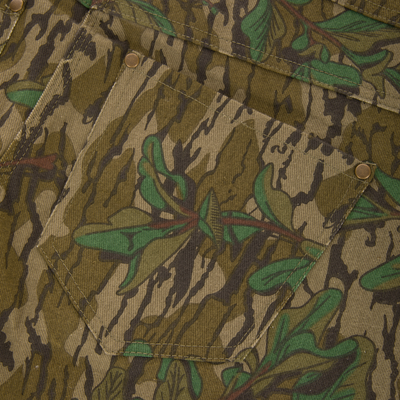 Throwback 80 Field Bib showcasing a close-up of the antique brass riveted pocket and camouflage fabric, highlighting durable craftsmanship and vintage design elements.