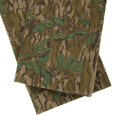 Throwback 80 Field Bib, featuring durable cotton twill with a camouflage pattern, triple needle stitching, and antique brass accents, ideal for tough outdoor tasks.