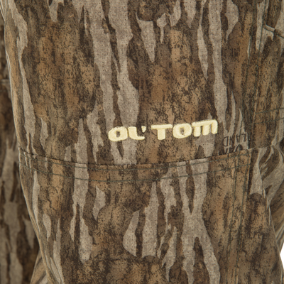 Close-up of Ol' Tom Early Bird SWT Pant, showcasing camo-patterned fabric with stitched seam and embroidered logo, highlighting its lightweight, insect-repellent, and water-resistant features.