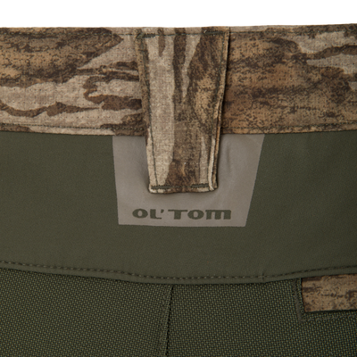 Close-up of Ol' Tom Early Bird Spider Web Technology Pant strap, showcasing camo pattern and logo, highlighting durable, insect-repellent fabric suitable for warm-weather hunting.