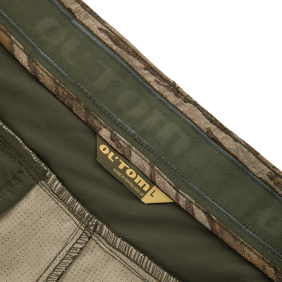 Close-up of Ol' Tom Early Bird SWT Pant waistband, showcasing olive-green stretch material, camouflage trim, and beige lining, highlighting its lightweight, breathable, insect-repellent design.