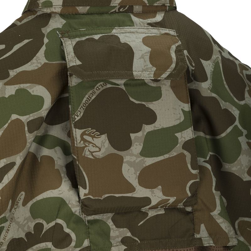 A close-up of the Youth Mesh Back Flyweight Shirt 2.0, a camouflage jacket with a logo patch and large chest pockets.