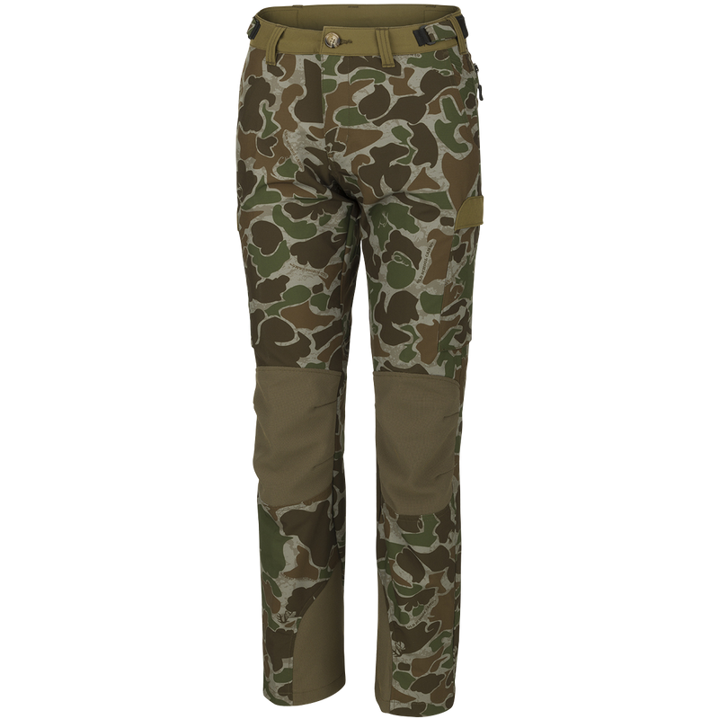 A pair of Women's Tech Stretch Turkey Pants, featuring a camouflage pattern. Designed for spring turkey hunting, these lightweight, moisture-wicking pants have reinforced knees, relaxed fit, and adjustable waistband for comfort. Includes mesh and zippered pockets for ventilation and storage.