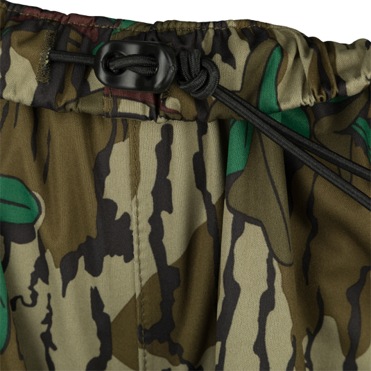 Ultralight Packable Rain Pant - Close-up of camouflage pants, perfect for spring showers during turkey season. Waterproof, windproof, and breathable. Fits easily in your vest with a compact 7" X 3" pack size. Designed to keep you dry with taped seams and a shock cord waist. Ideal for outdoor activities like big game hunting, waterfowl hunting, turkey hunting, and fishing.
