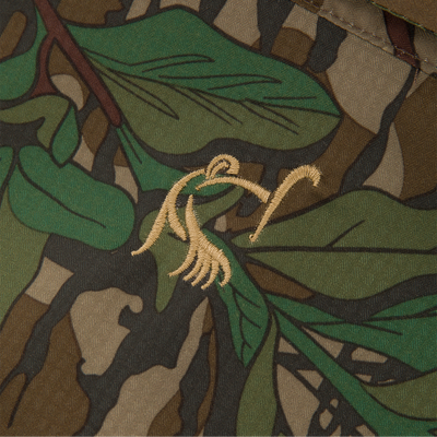 Close-up of Men's Camo Wingshooter Trey Shirt, highlighting its camouflage fabric and technical features like hidden pockets and vented design.