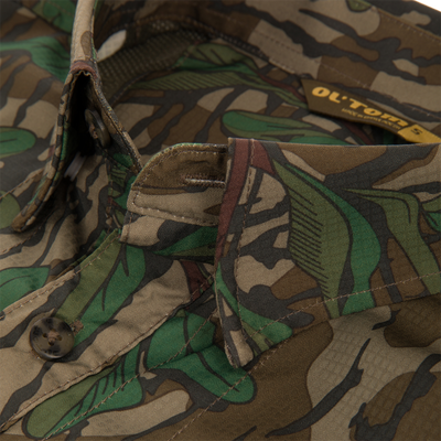 Men's Camo Wingshooter Trey Shirt close-up, featuring camouflage fabric, hidden button-down collar, vented cape back, and button-through flap chest pockets.