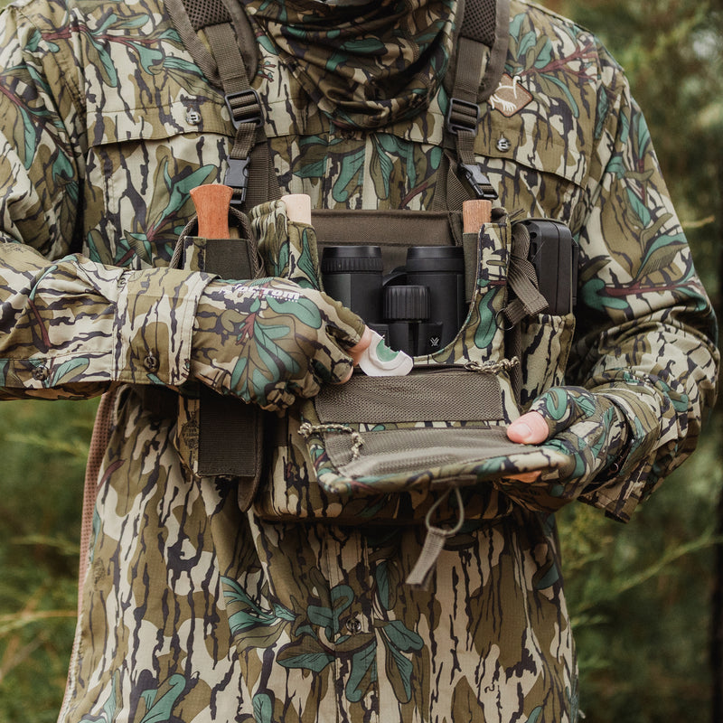 Man in outdoors reaching into open chest pack.