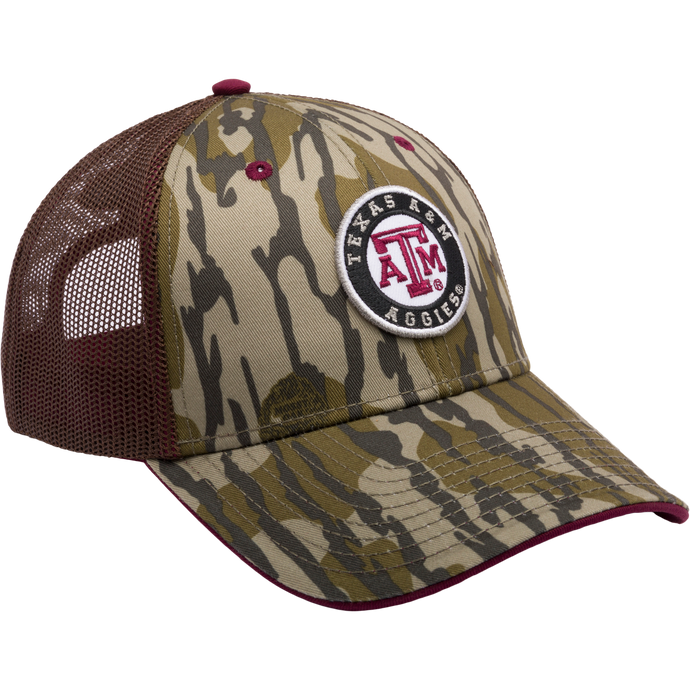 A Texas A&M Bottomland Mesh Back Cap featuring Mossy Oak Camo pattern. Structured with poly twill front, mesh back, X-Peak visor, 3D logo embroidery, and snap-back closure. Ideal for hunting enthusiasts.