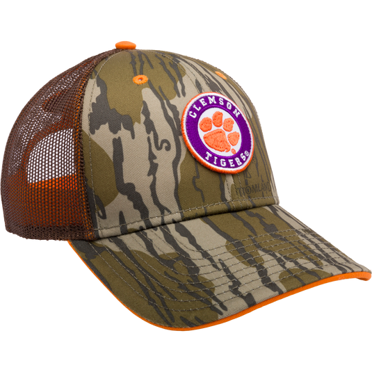 Clemson Bottomland Mesh Back Cap with Mossy Oak Camo pattern. Structured trucker cap with embroidered college logo, mesh panels, and snap-back closure. Ideal for hunting and outdoor enthusiasts.