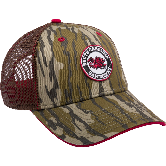A South Carolina Bottomland Mesh Back Cap by Drake Waterfowl. Features Mossy Oak Bottomland Camo pattern, 3D embroidered college logo, structured crown, mesh panels, and X-Peak visor.