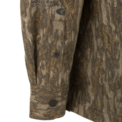 Long-sleeved cuff of the Spoonie Campfire Hoodie featuring a brown and tan camouflage pattern with Mossy Oak Bottomland branding.