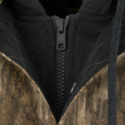 Close-up of a Spoonie Campfire Hoodie featuring a camouflage patterned jacket with a black hood and a black plastic zipper.