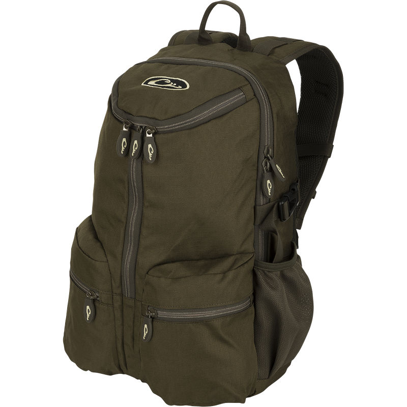 A compact, functional green backpack with zippers, perfect for casual or hunting use. Features padded shoulder straps, large interior storage, and external carry straps. Ideal for storing essential items with easy accessibility. From Drake Waterfowl's High-Quality Hunting Gear collection.