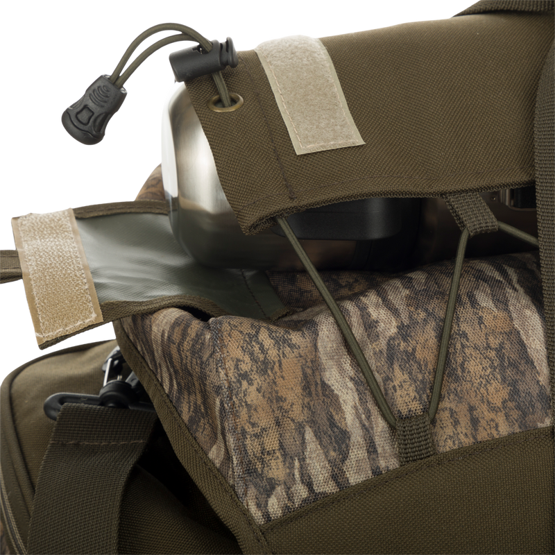A close-up of the Large Blind Bag by Drake Waterfowl, featuring 18 pockets for organized gear storage. Waterproof construction with durable Nylon/TPU bottom. Adjustable shoulder strap and various storage compartments. Dimensions: 18