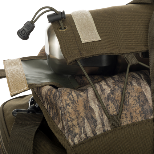 A close-up of the Large Blind Bag by Drake Waterfowl, featuring 18 pockets for organized gear storage. Waterproof construction with durable Nylon/TPU bottom. Adjustable shoulder strap and various storage compartments. Dimensions: 18