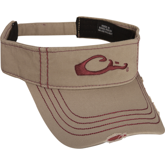 A tan visor with a red logo, featuring raised logo embroidery on the front and color-matched stitching on the bill. Velcro back closure. Made of 100% cotton. Low profile fit. Final Sale. Drake DH Logo Visor.