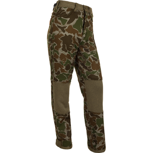 A pair of camouflage pants with Agion Active XL® scent control technology, designed for quiet and comfortable hunting. Made of soft-shell fabric with a micro-fleece lining for warmth and comfort. Features adjustable waist, hook and loop ankle, and elastic foot stirrups. Ideal for Mid to Late Season deer stand.