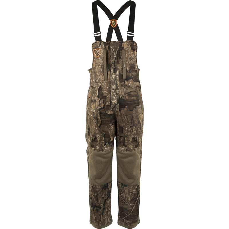 A youth silencer bib with Agion Active XL, featuring camouflage overalls with straps and vertical pockets for hunting gear.