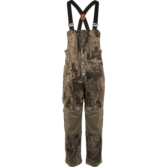 A youth silencer bib with Agion Active XL, featuring camouflage overalls with straps and vertical pockets for hunting gear.