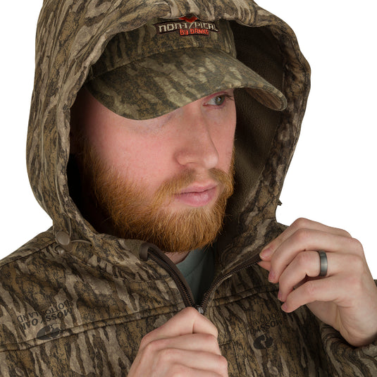 A man wearing the Endurance 1/4 Zip Jacket, a camouflage hat, and a hat.